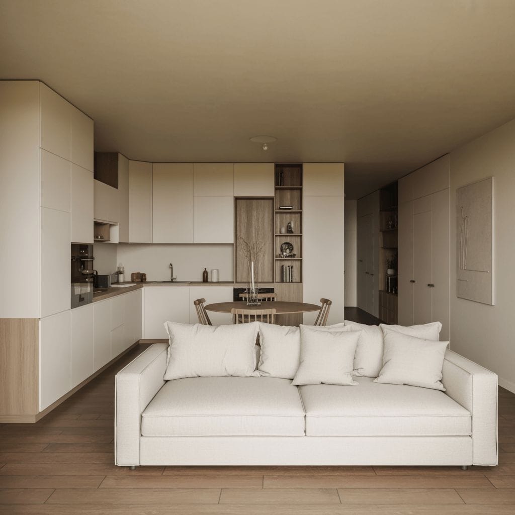 Un salon moderne et ouvert avec un canapé beige, du parquet et une cuisine avec des armoires blanches et en bois en arrière-plan.